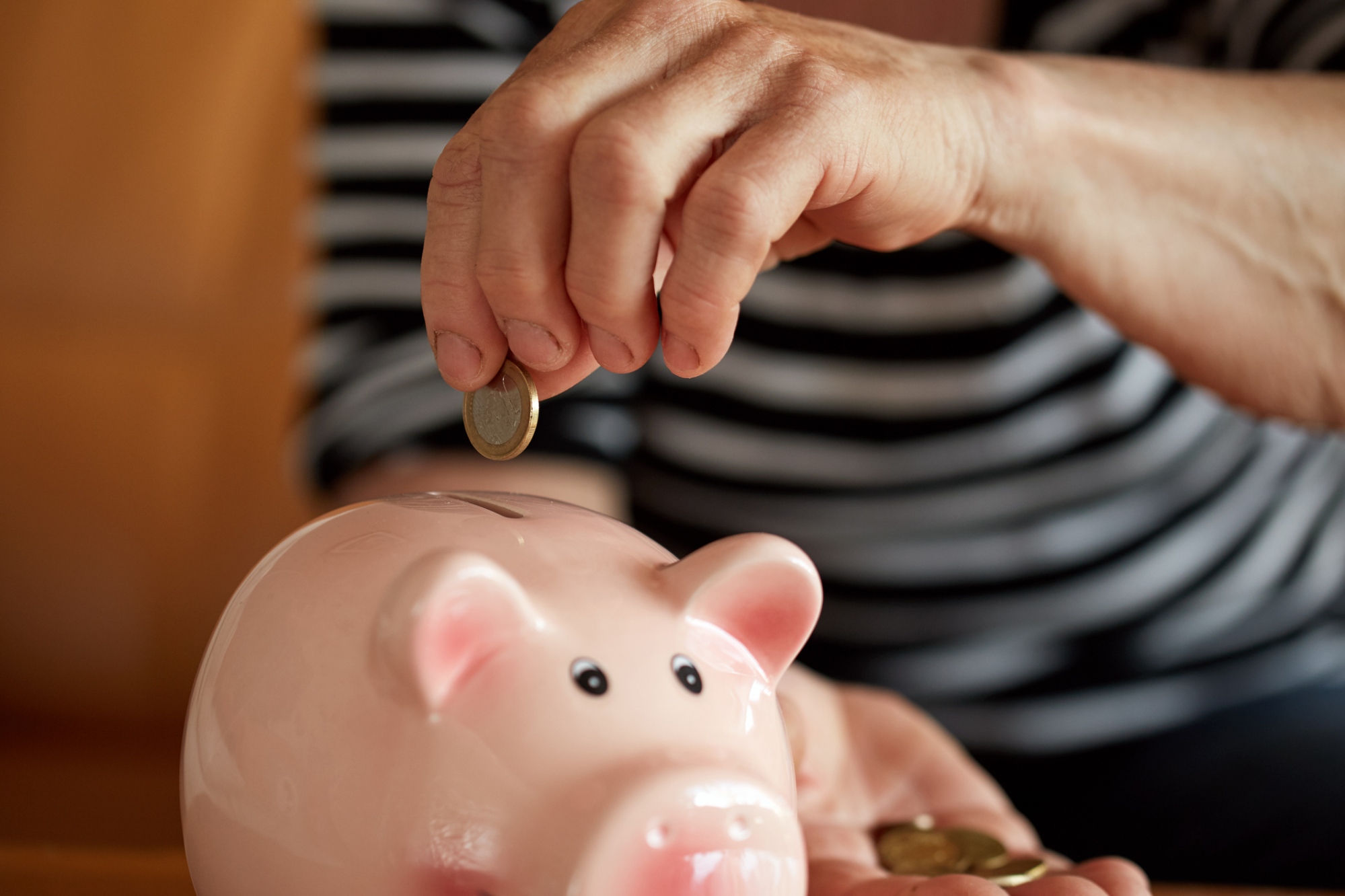 Inserting coin in piggy bank